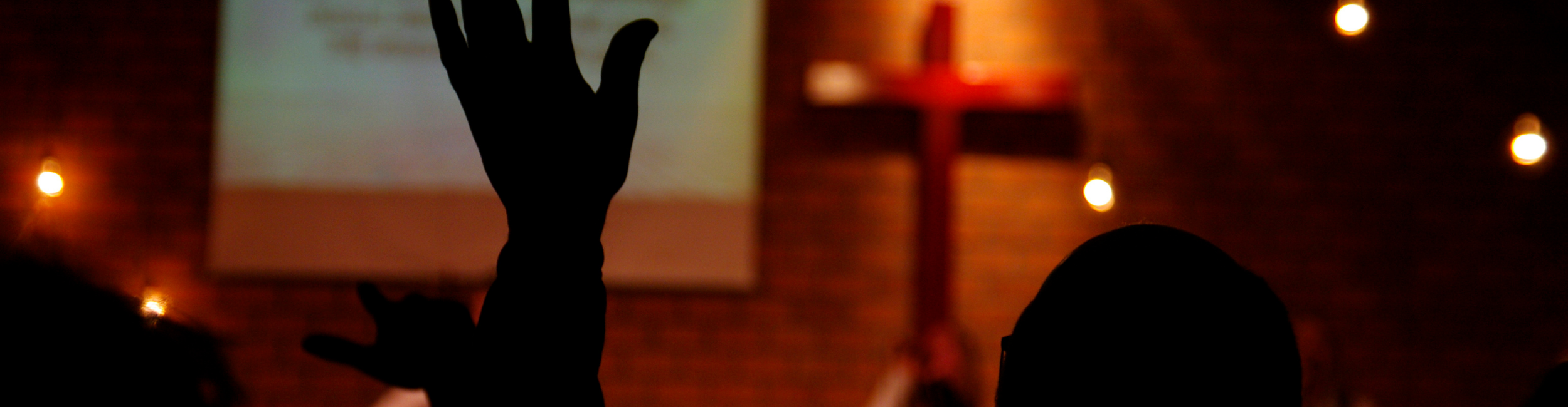 Worshippers with hands raised before a cross at Good Shepherd Church